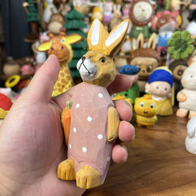 Solid basswood carved bunny holding a carrot figurine for shelf display