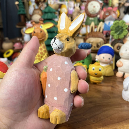 Solid basswood carved bunny holding a carrot figurine for shelf display