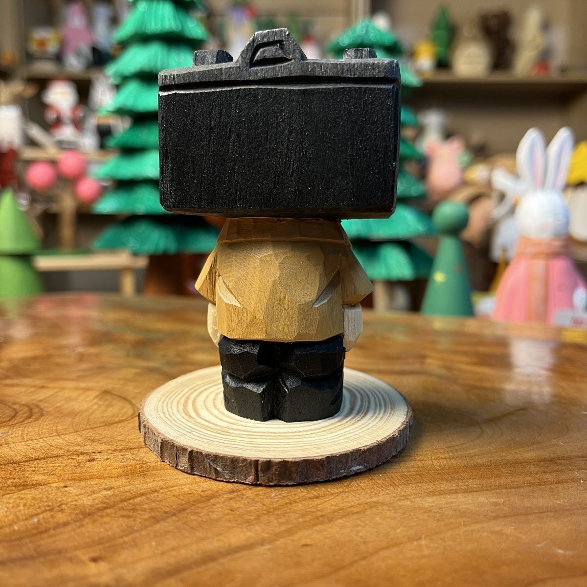 Hand-finished camera guy wooden figurine standing on a wooden studio desk
