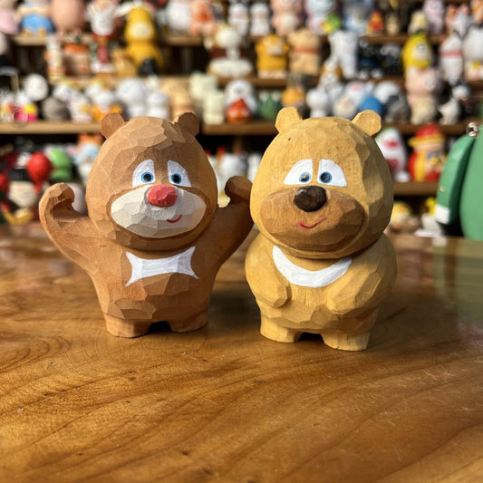 Pair of hand-finished wooden bear brother figurines sitting on a wooden desk