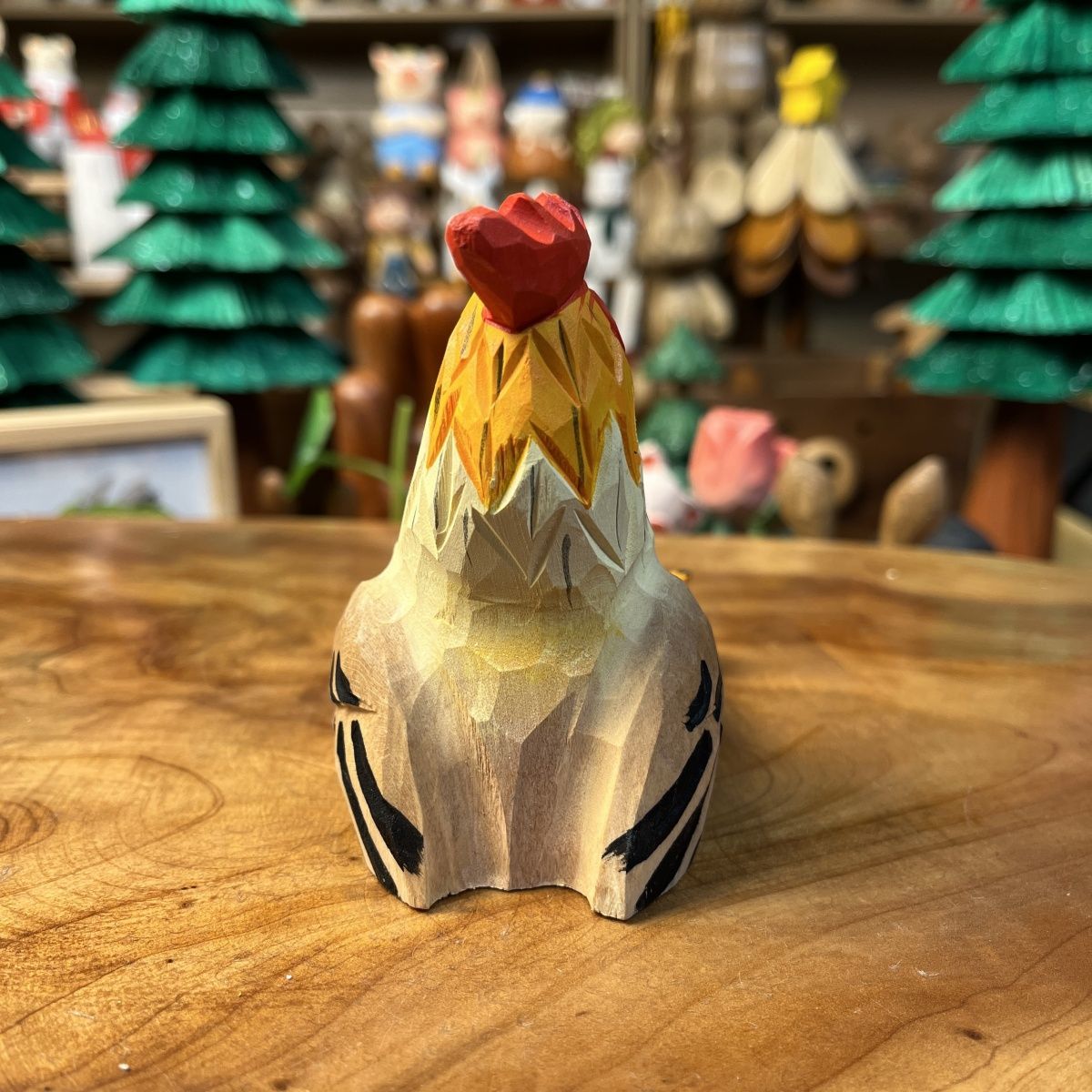Hand-finished carved wooden rooster phone stand holding a smartphone on a desk