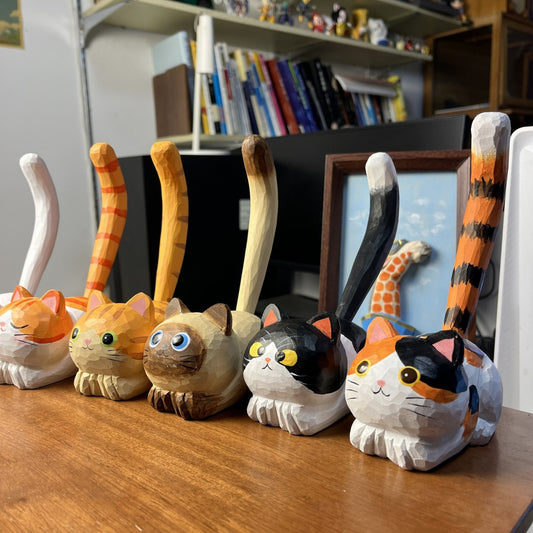 Wooden lucky cat pen holder holding a pen on a cozy office desk