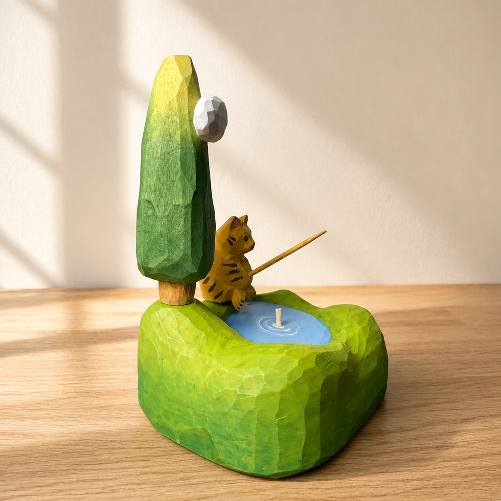 Playful fishing cat wooden figurine standing on a sculpted landscape base