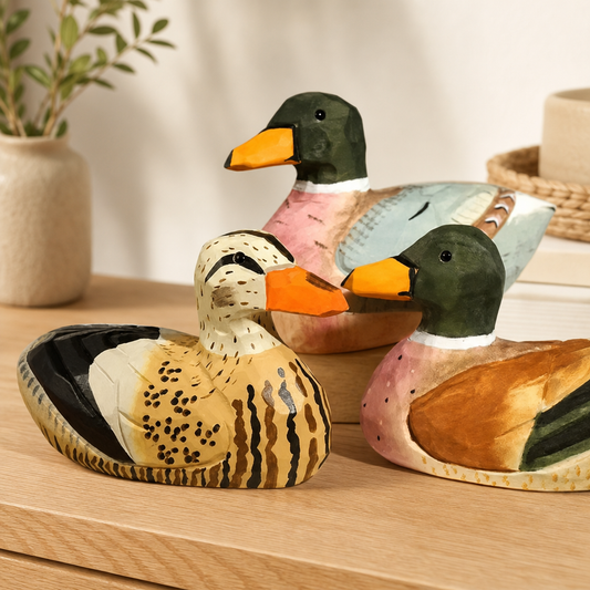 Pair of painted wooden duck figurines resting on a warm wooden tabletop.